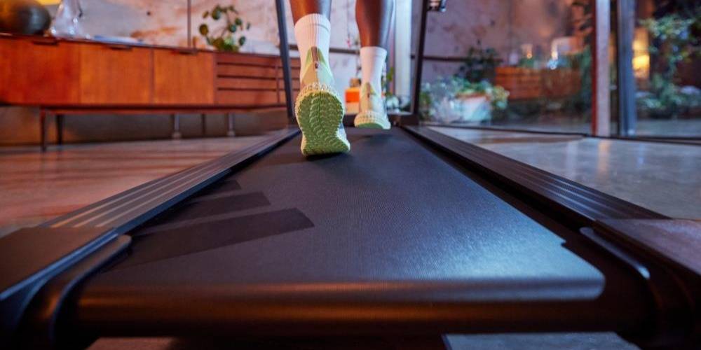 Løper på Adidas tredemølle med skjerm og treningsapper